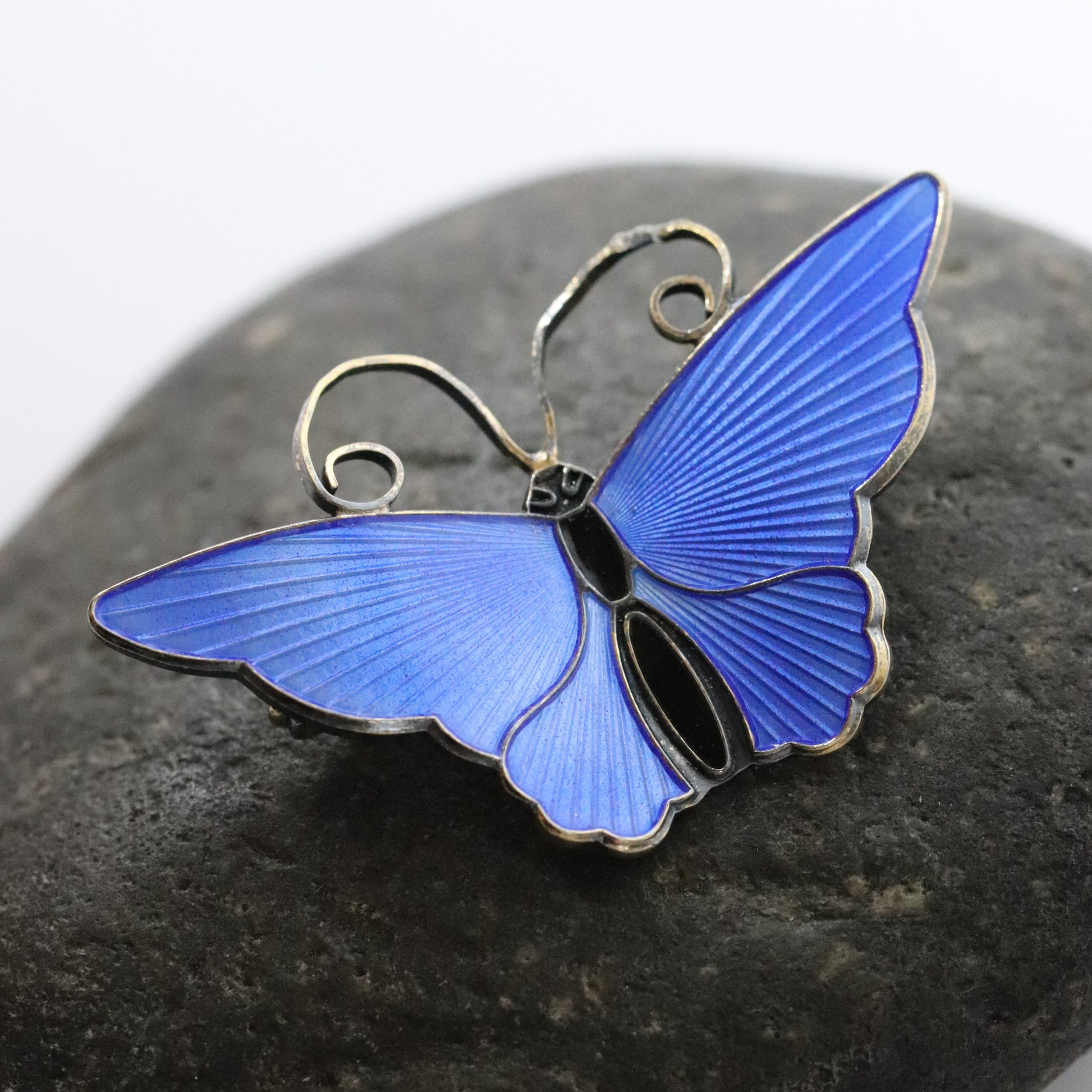 David Andersen enamel butterfly brooch in electric blue on a dark stone background