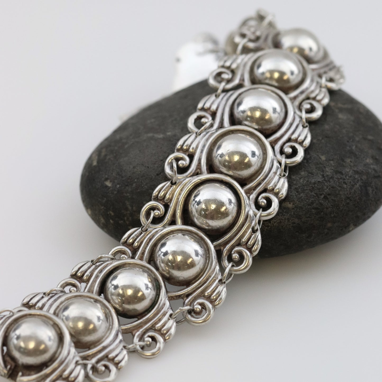 Los Castillo Taxco silver cabochon bracelet with ornate vintage design on stone background