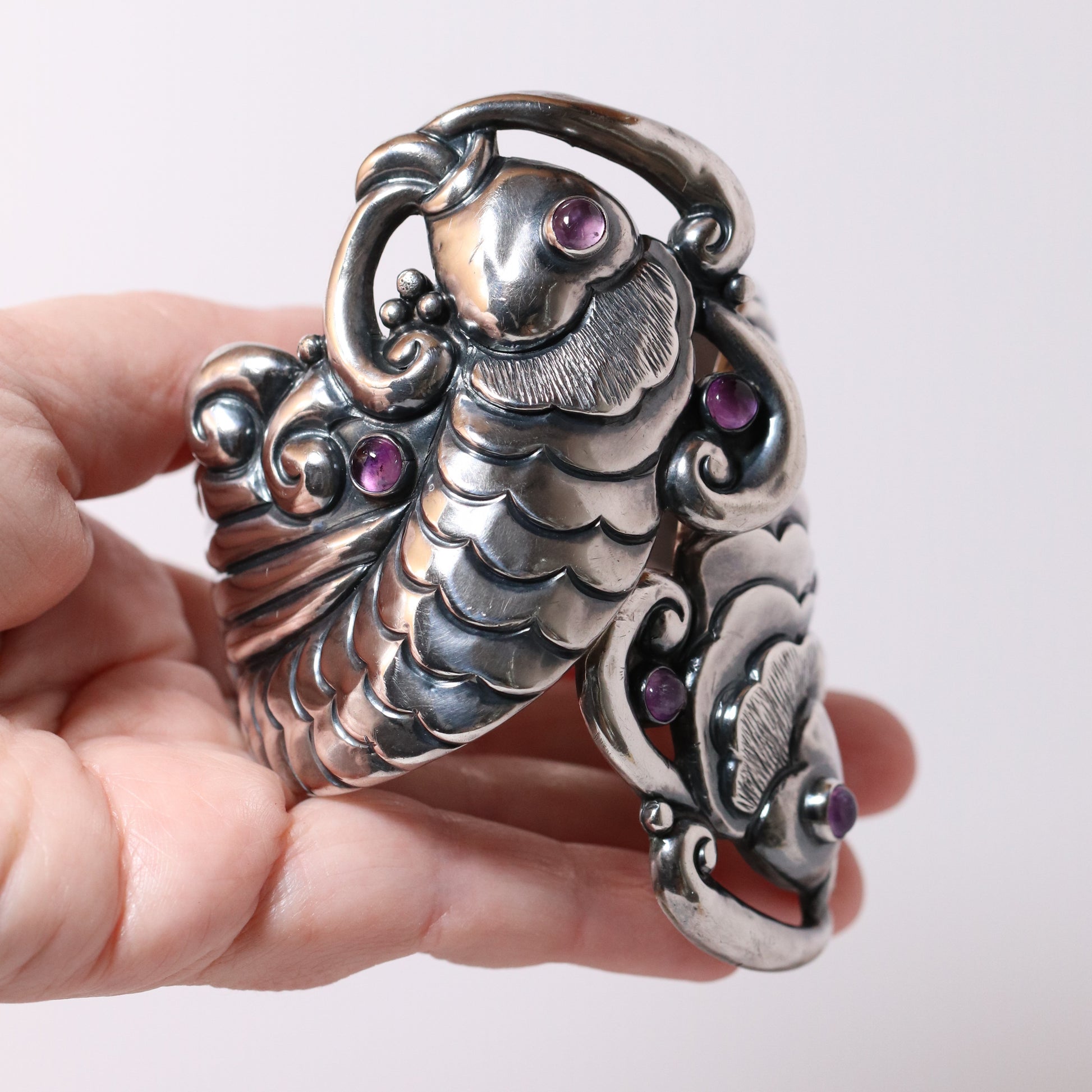 Margot de Taxco vintage silver koi bracelet with purple gemstones held in hand