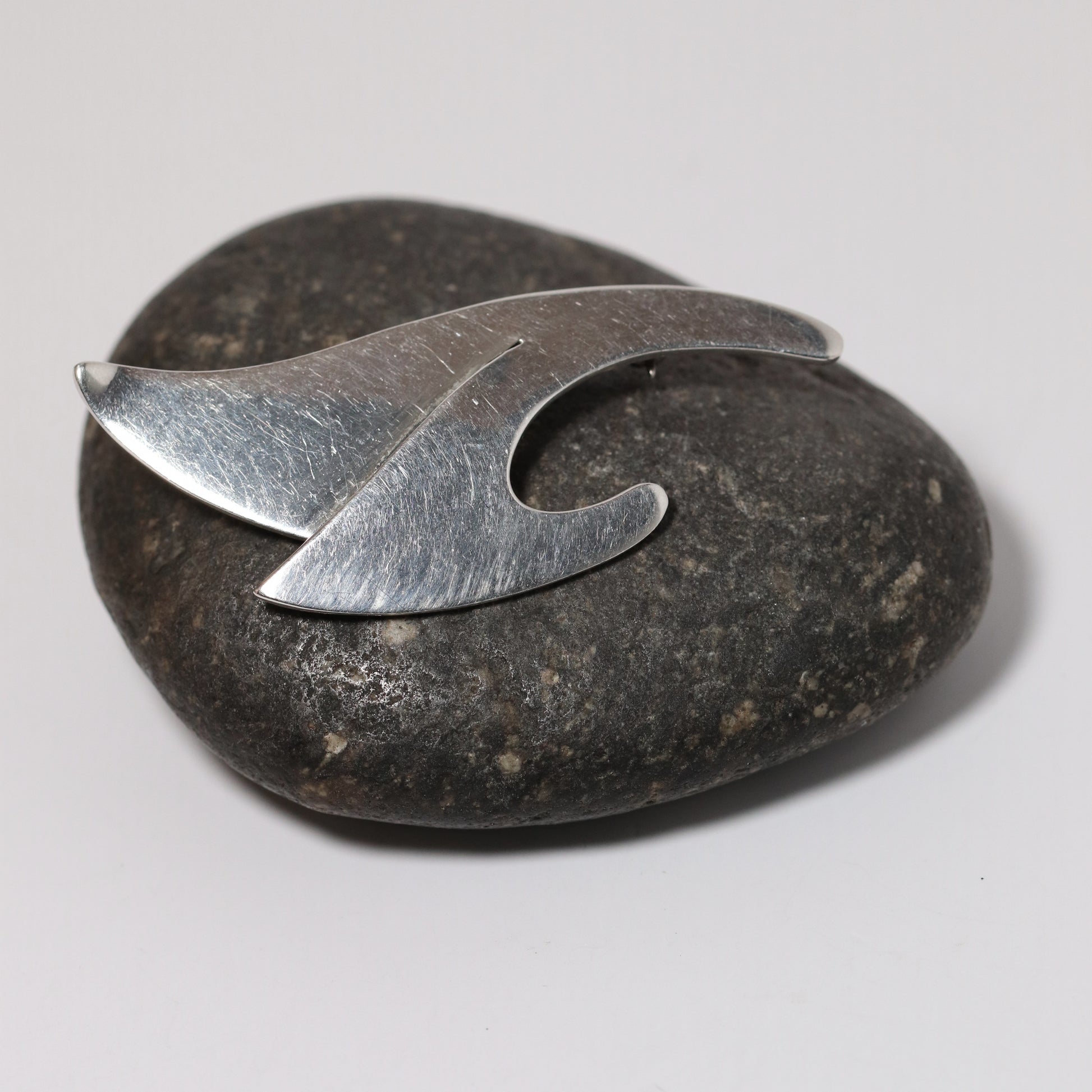 Sigi Pineda abstract sterling silver brooch from Taxco Mexico on a dark stone