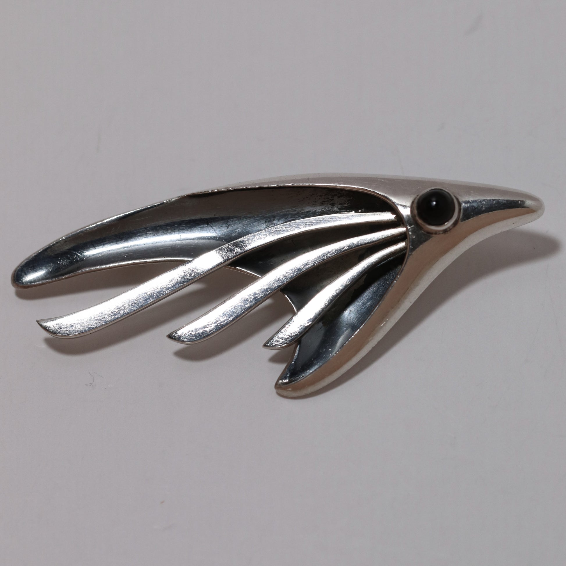 Sigi Pineda abstract silver fish or bird brooch with black stone eye on white background