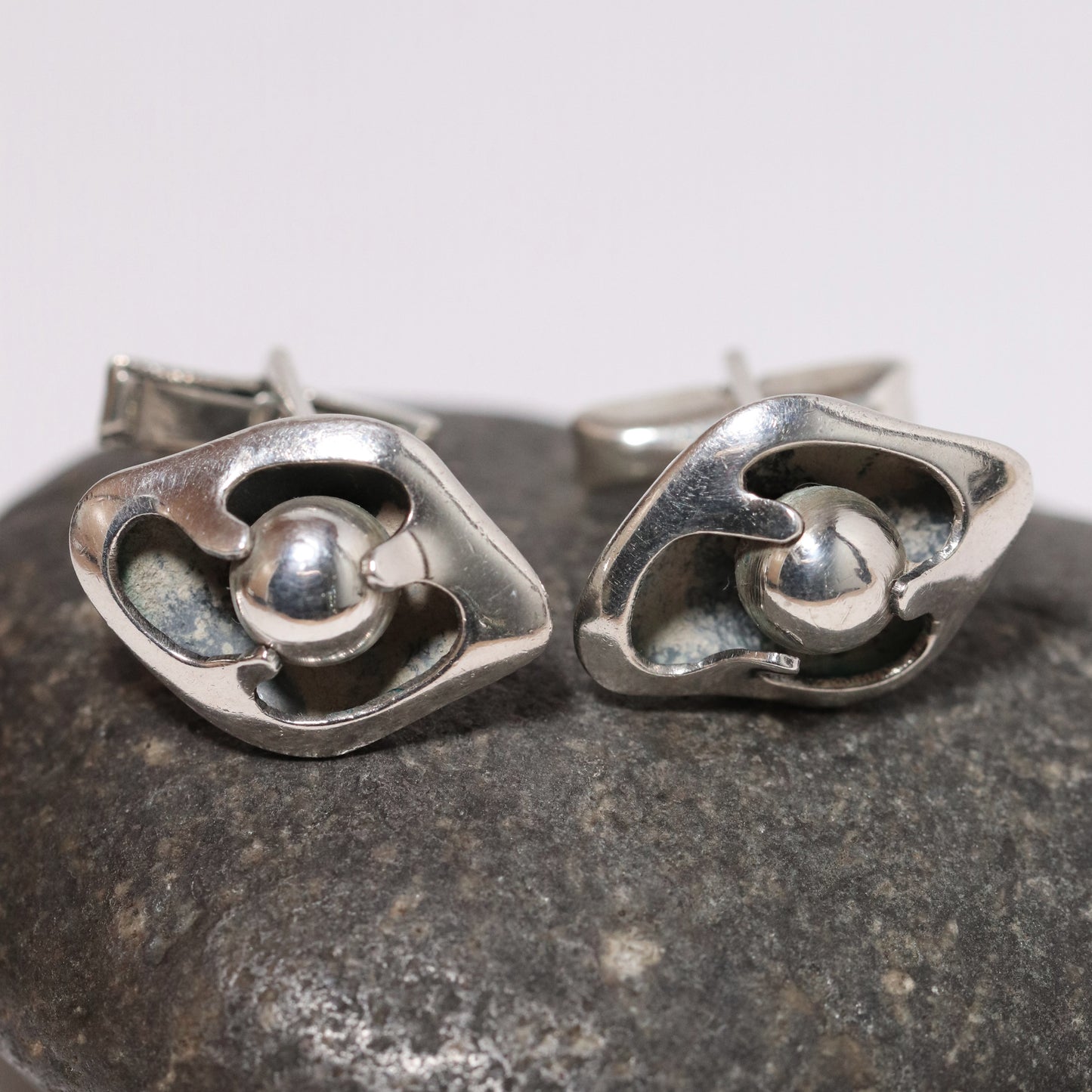 Sigi Pineda Taxco silver cufflinks with encased ball design on stone background