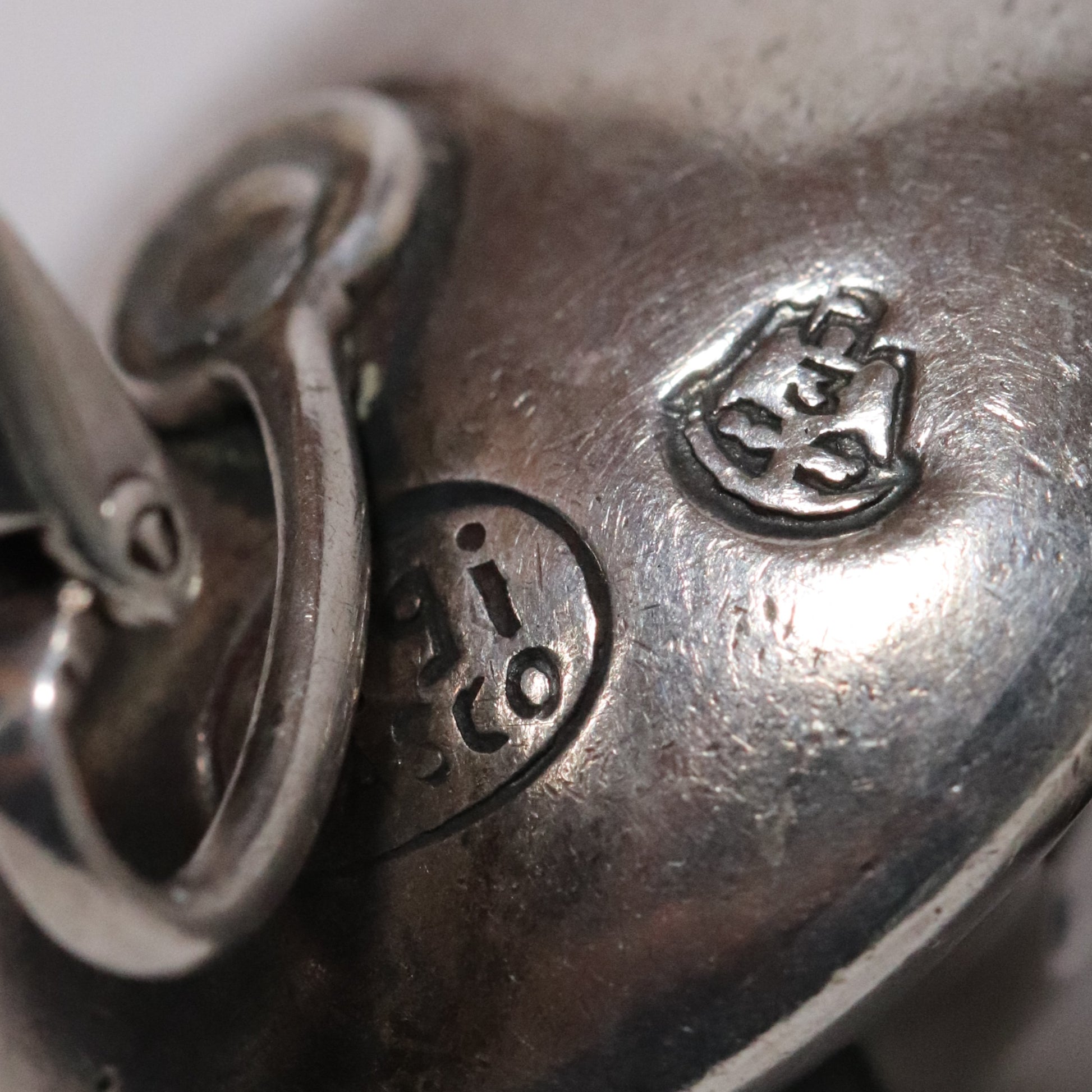 Close-up of Sigi Pineda Taxco silver earring with maker's hallmark and detailed stamp.