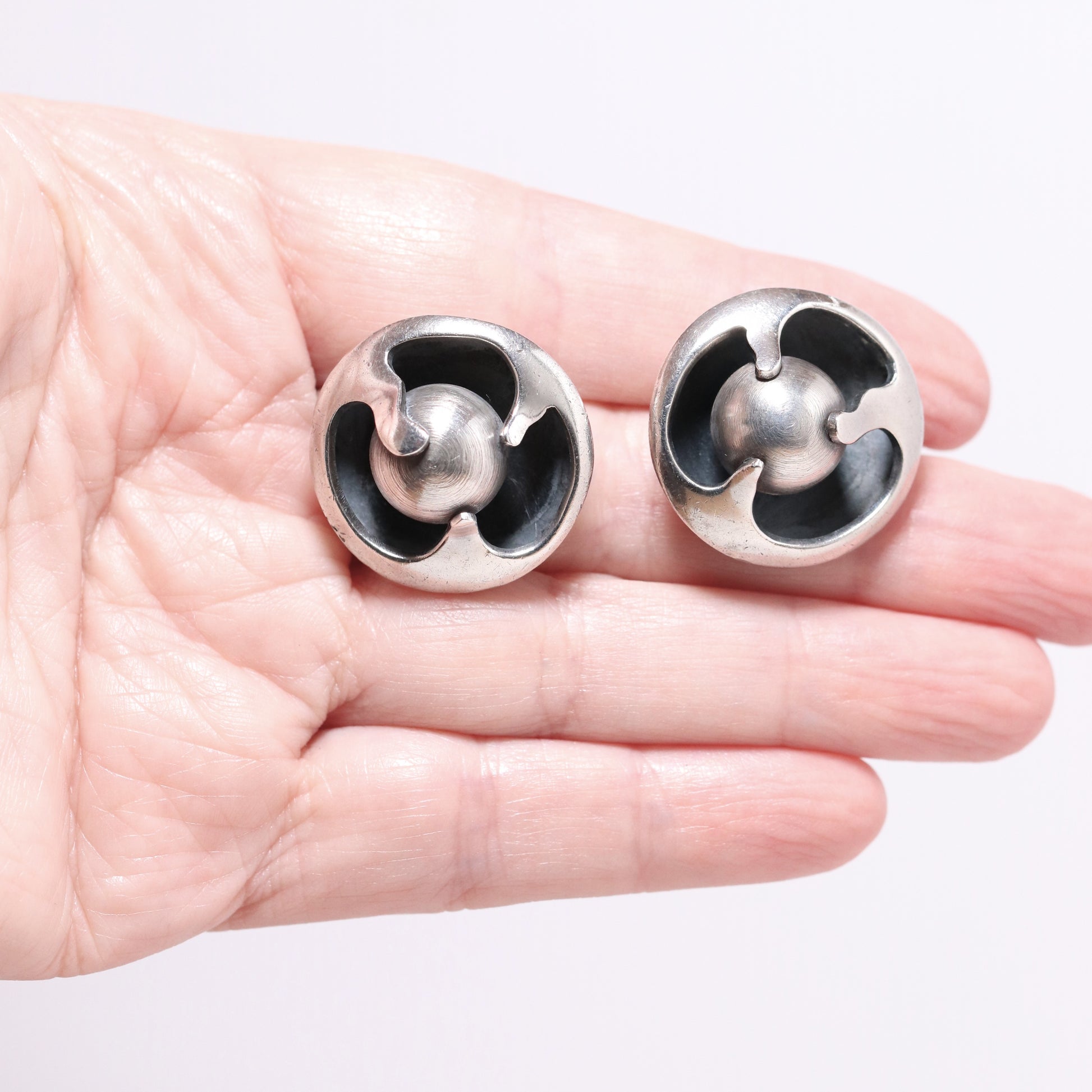 Sigi Pineda large encased ball Taxco silver earrings with sculptural design on a hand