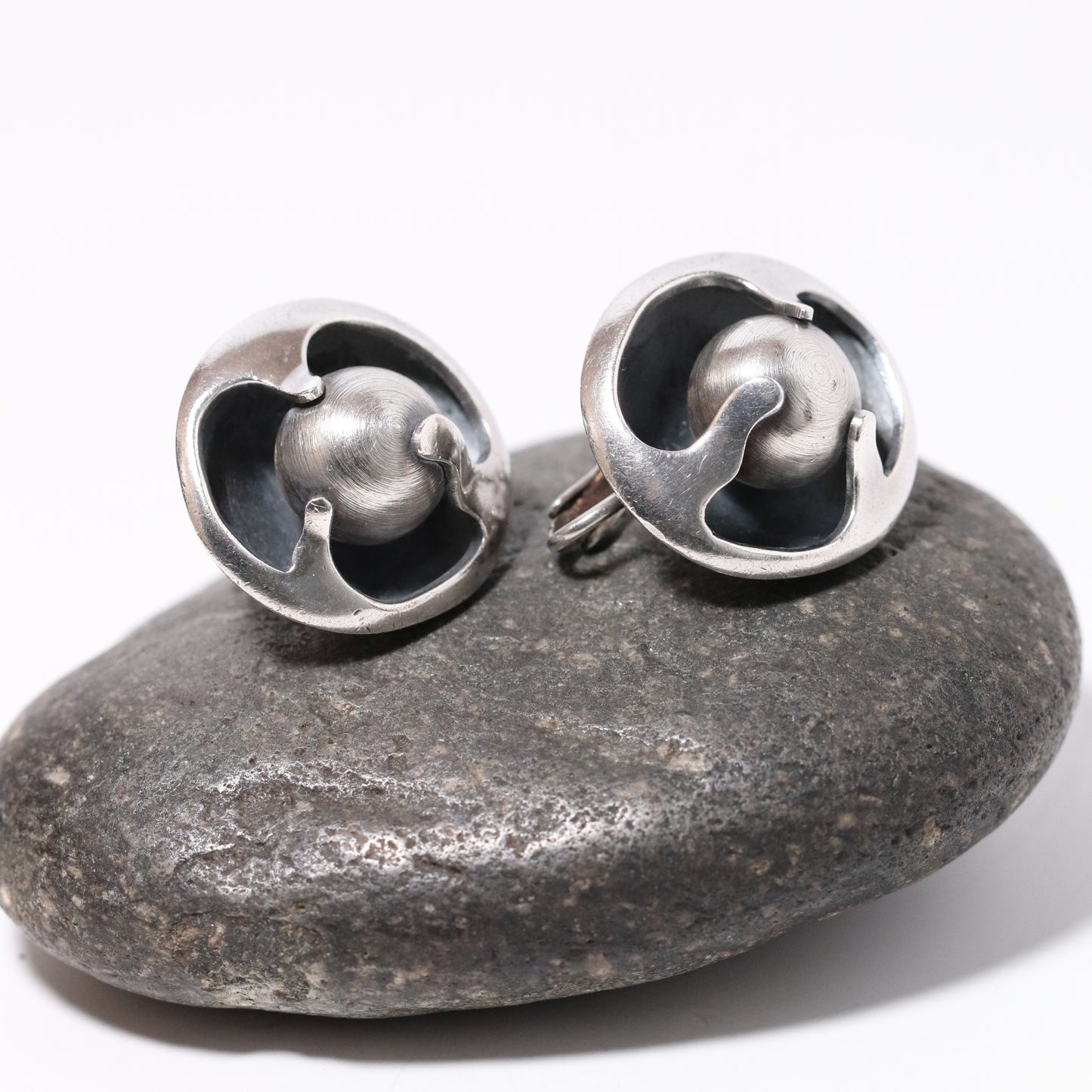 Sigi Pineda Taxco silver ball encased earrings on stone background