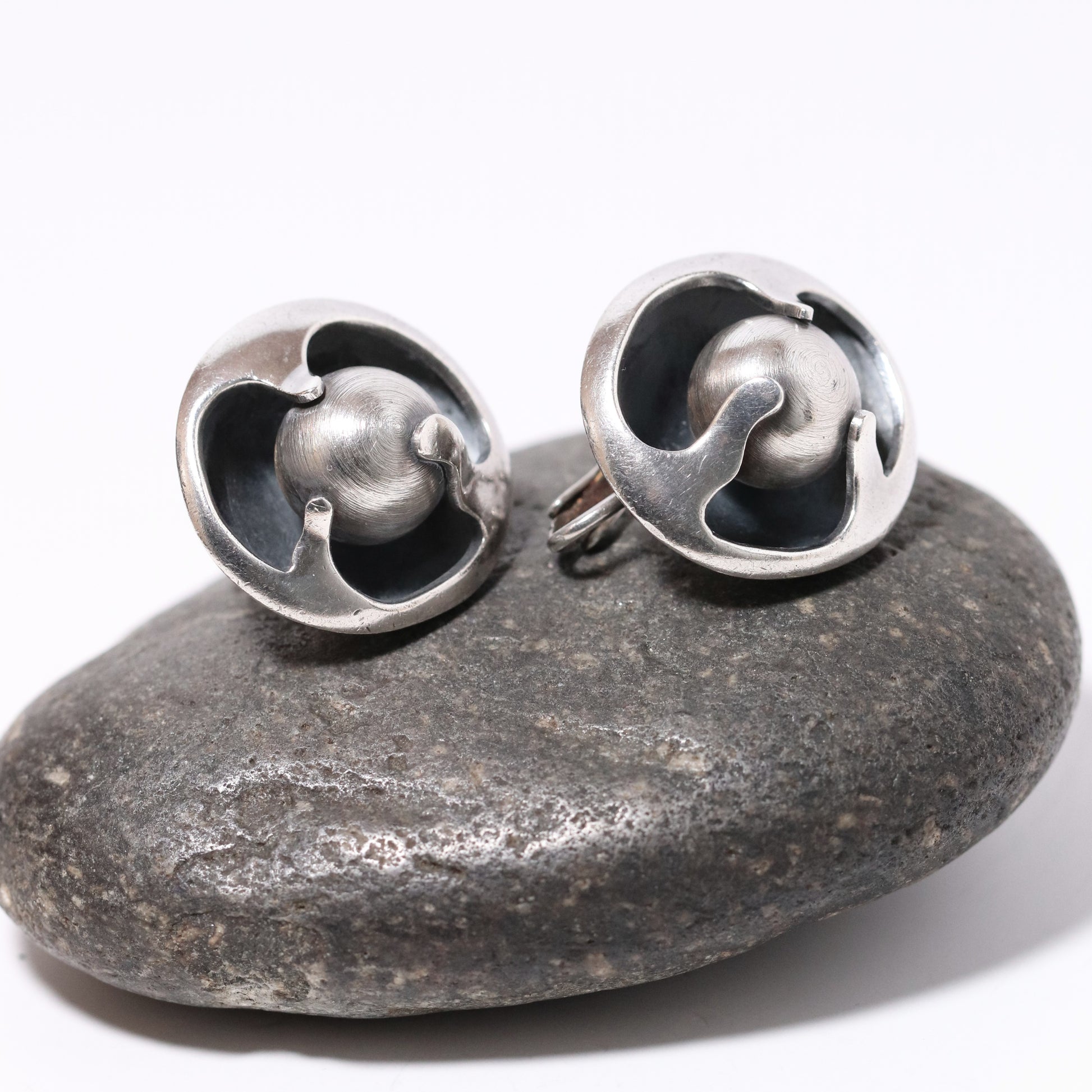 Sigi Pineda Taxco silver ball encased earrings on stone background