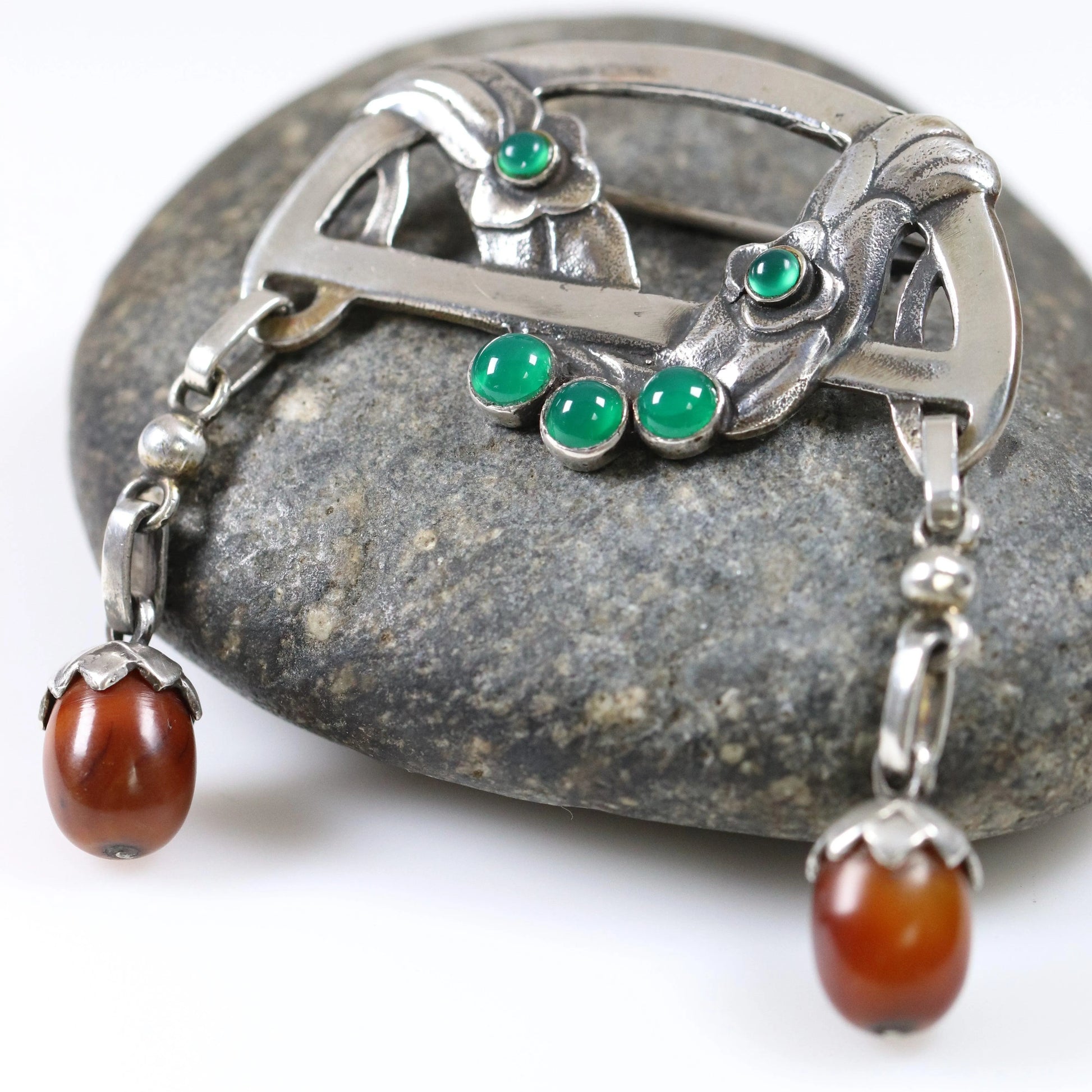 Antique Georg Jensen silver floral brooch with amber and chrysoprase on a gray stone