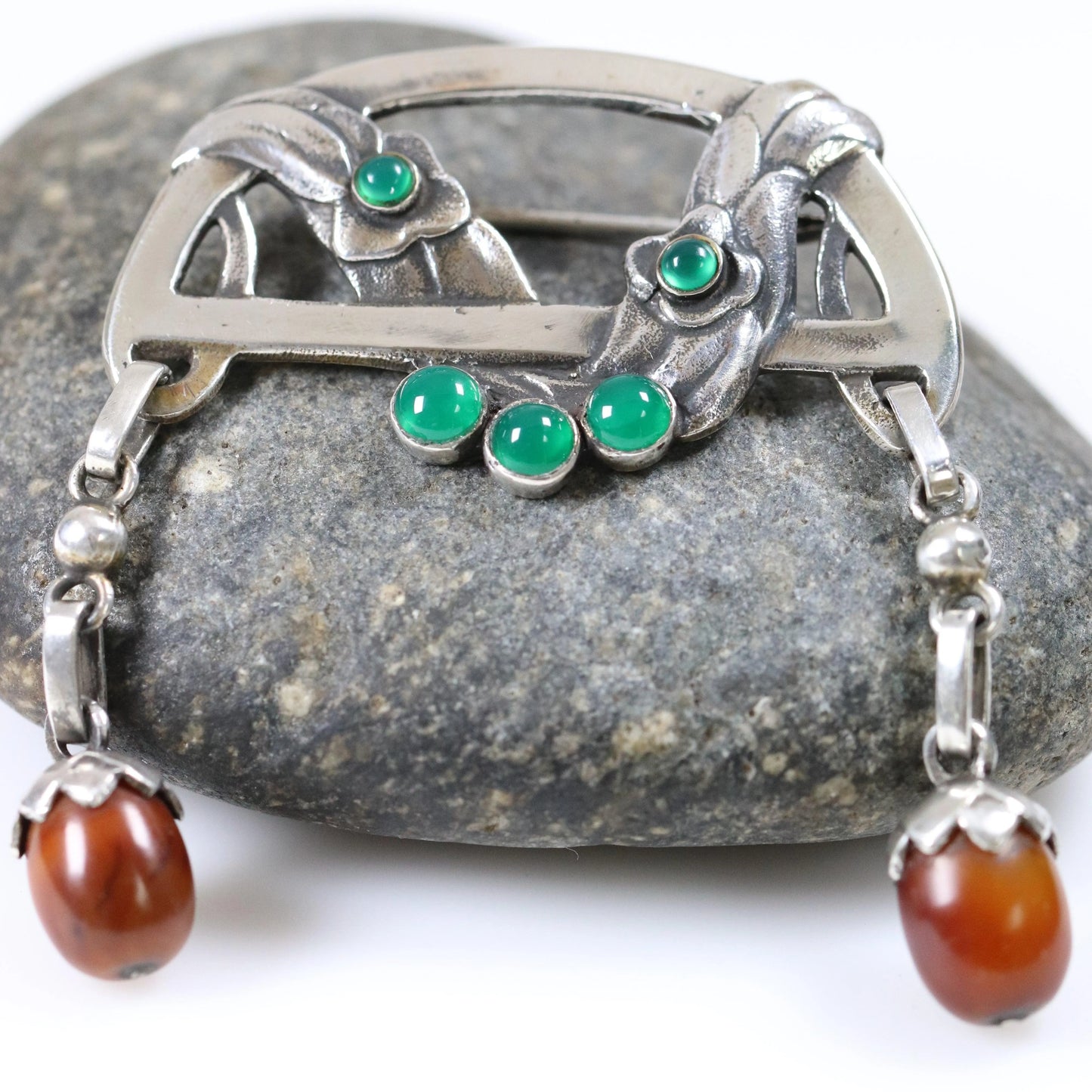 Antique Georg Jensen floral brooch with amber and chrysoprase on a smooth stone