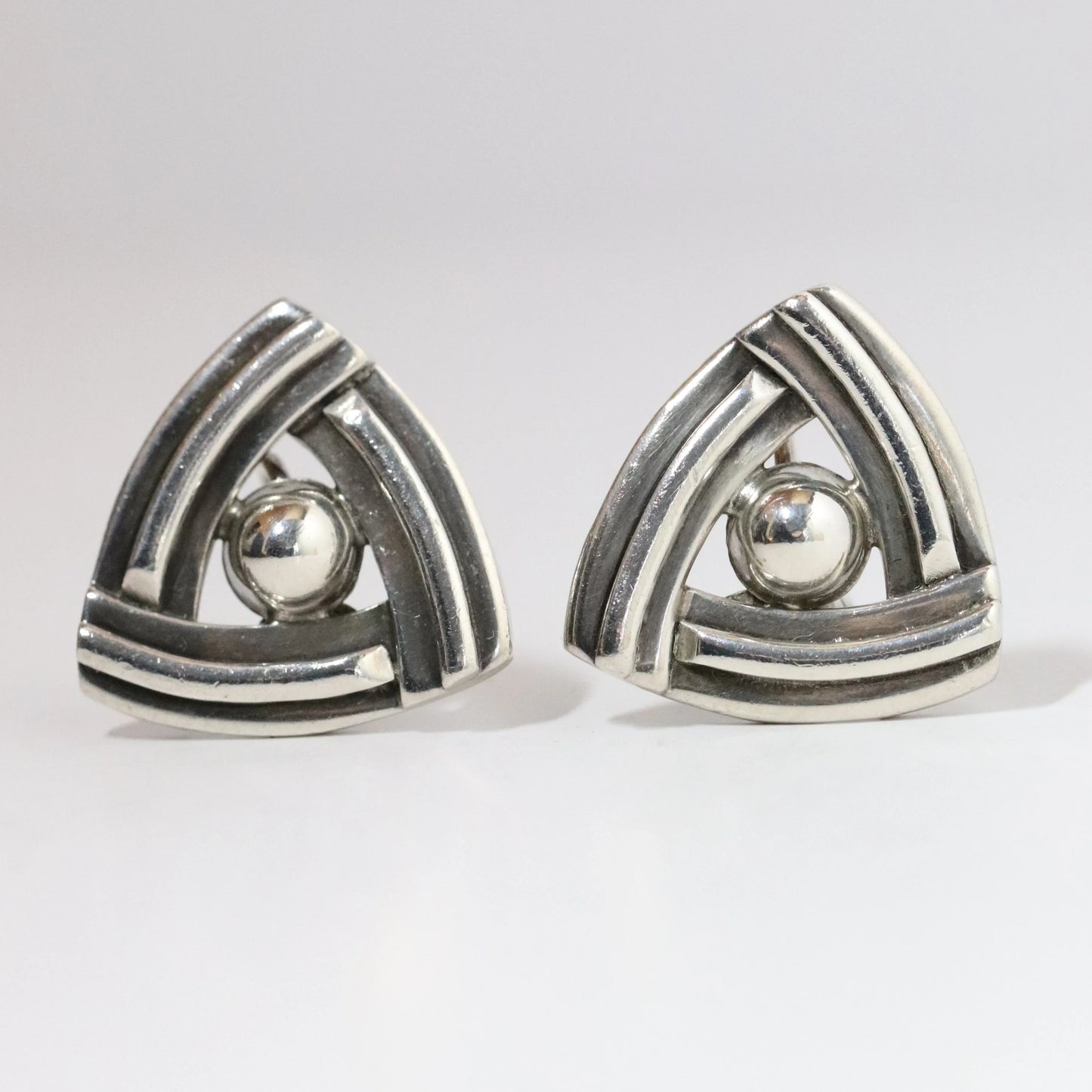 Vintage geometric silver earrings with triangular design and central silver ball on white background