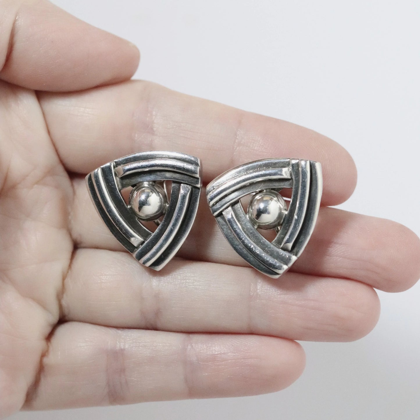 Hand holding vintage geometric sterling silver earrings with triangular design