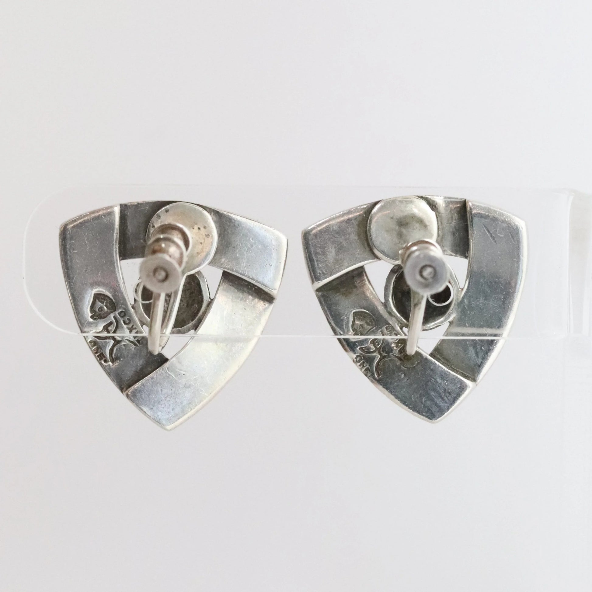 Pair of vintage silver geometric stud earrings on a clear stand, showing stamped hallmarks