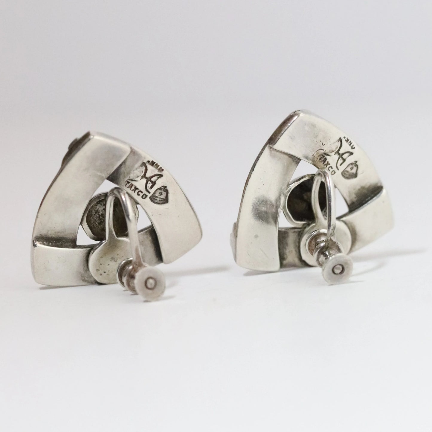 Pair of vintage silver screw back earrings with geometric triangle design on white background
